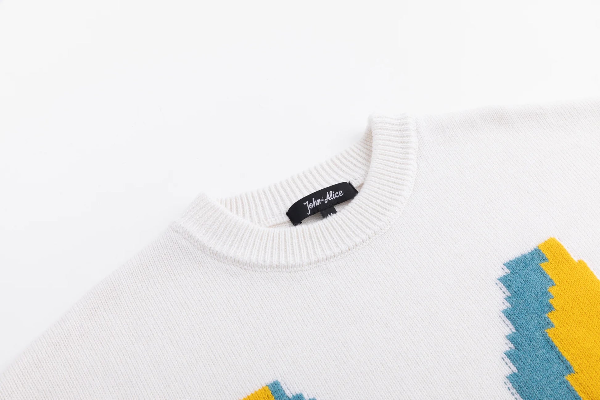 Close-up of the crew neckline on the ivory jumper, with part of the front motif visible.