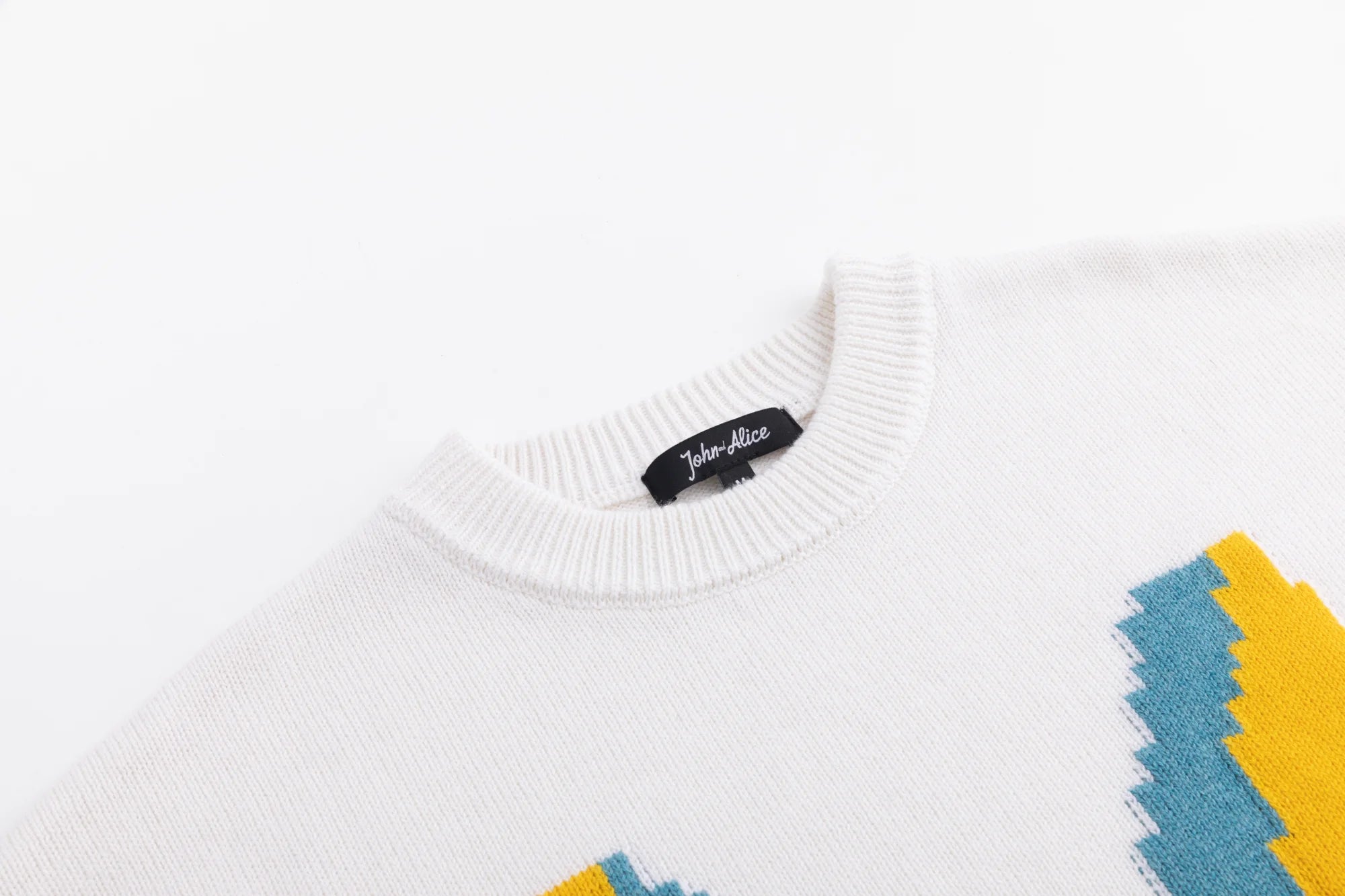 Close-up of the crew neckline on the ivory jumper, with part of the front motif visible.
