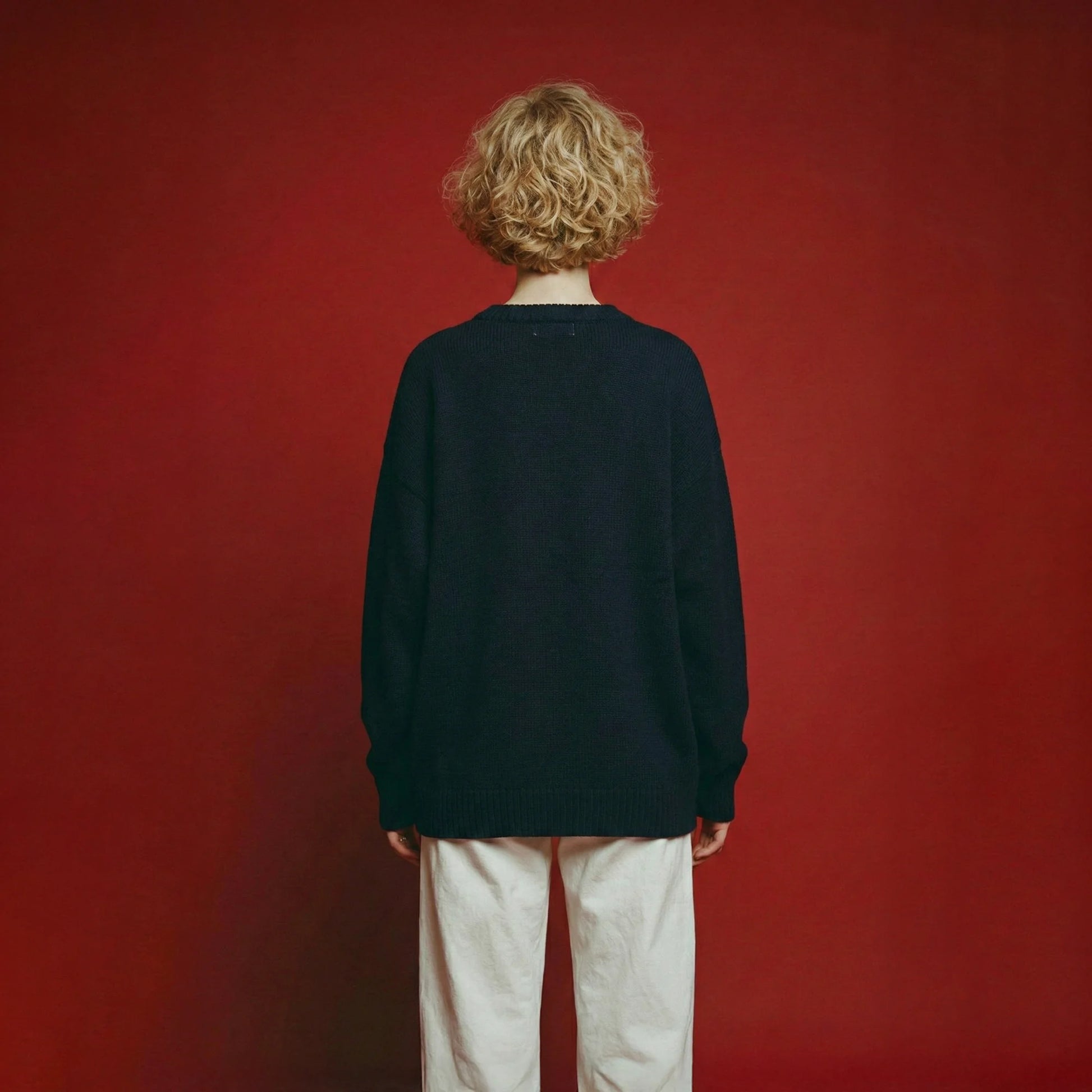 Back view of woman wearing a navy oversized wool jumper with drop shoulders.