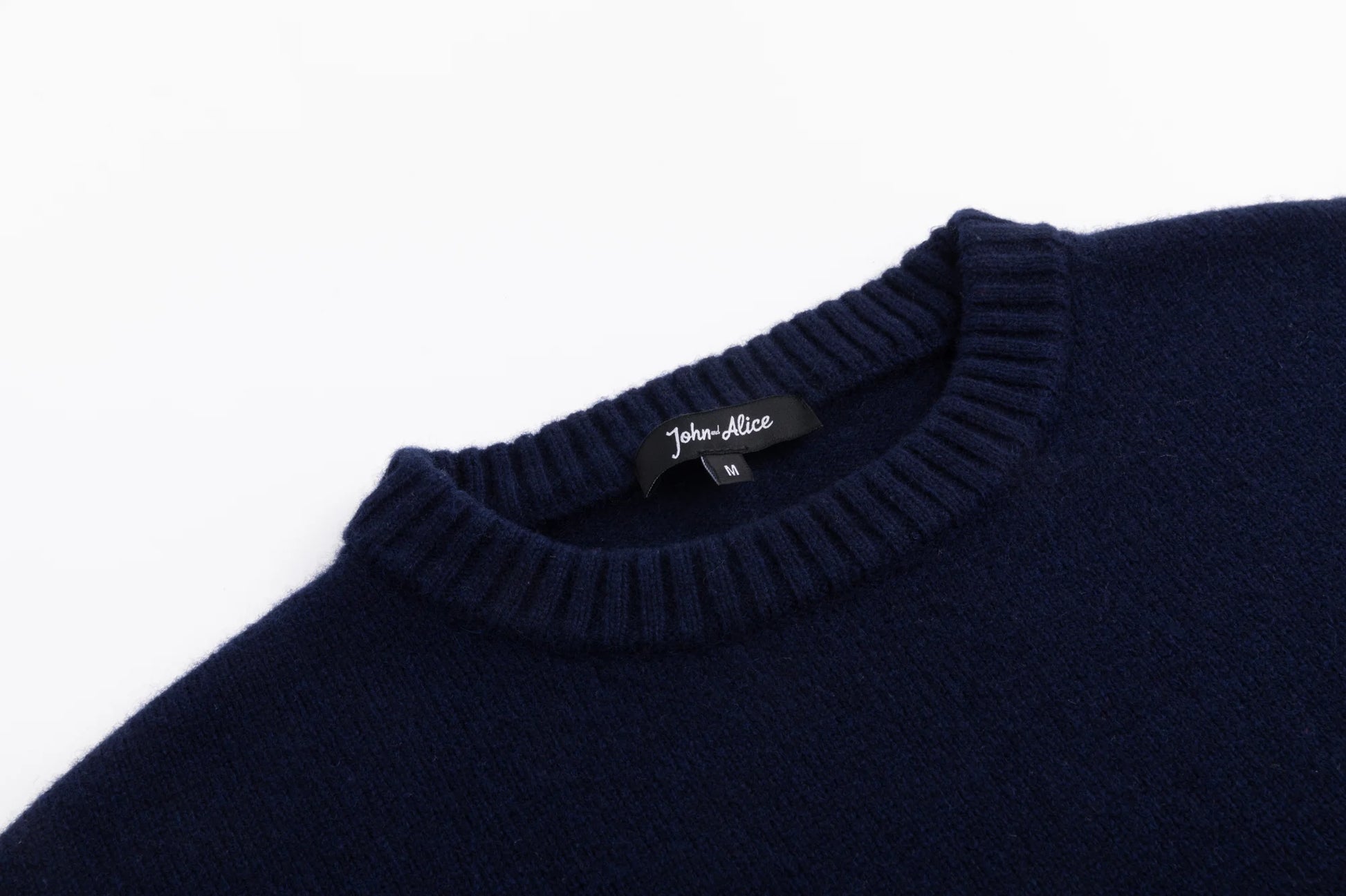 Close-up of the ribbed crew neckline on the navy wool jumper.