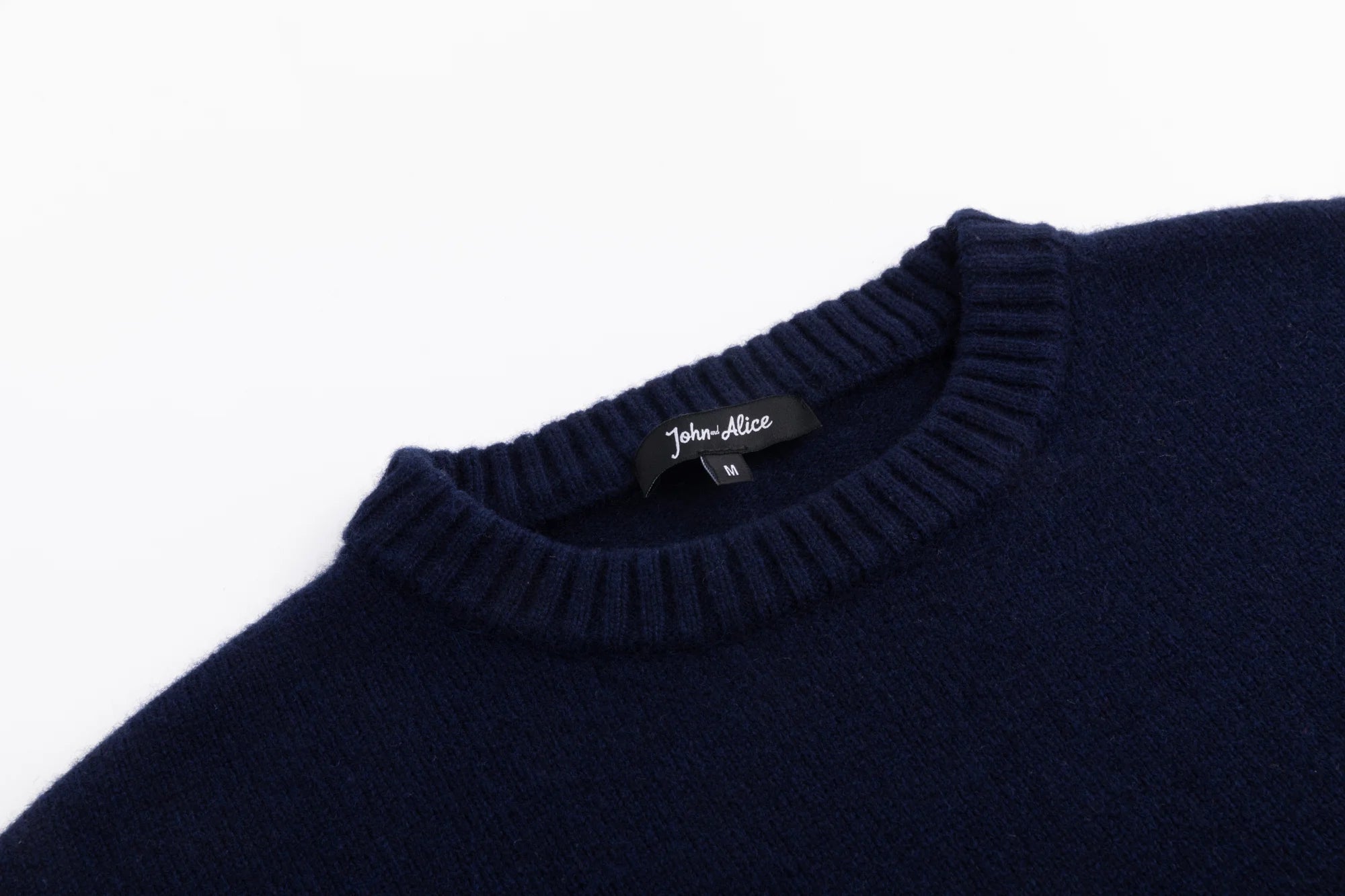 Close-up of the ribbed crew neckline on the navy wool jumper.