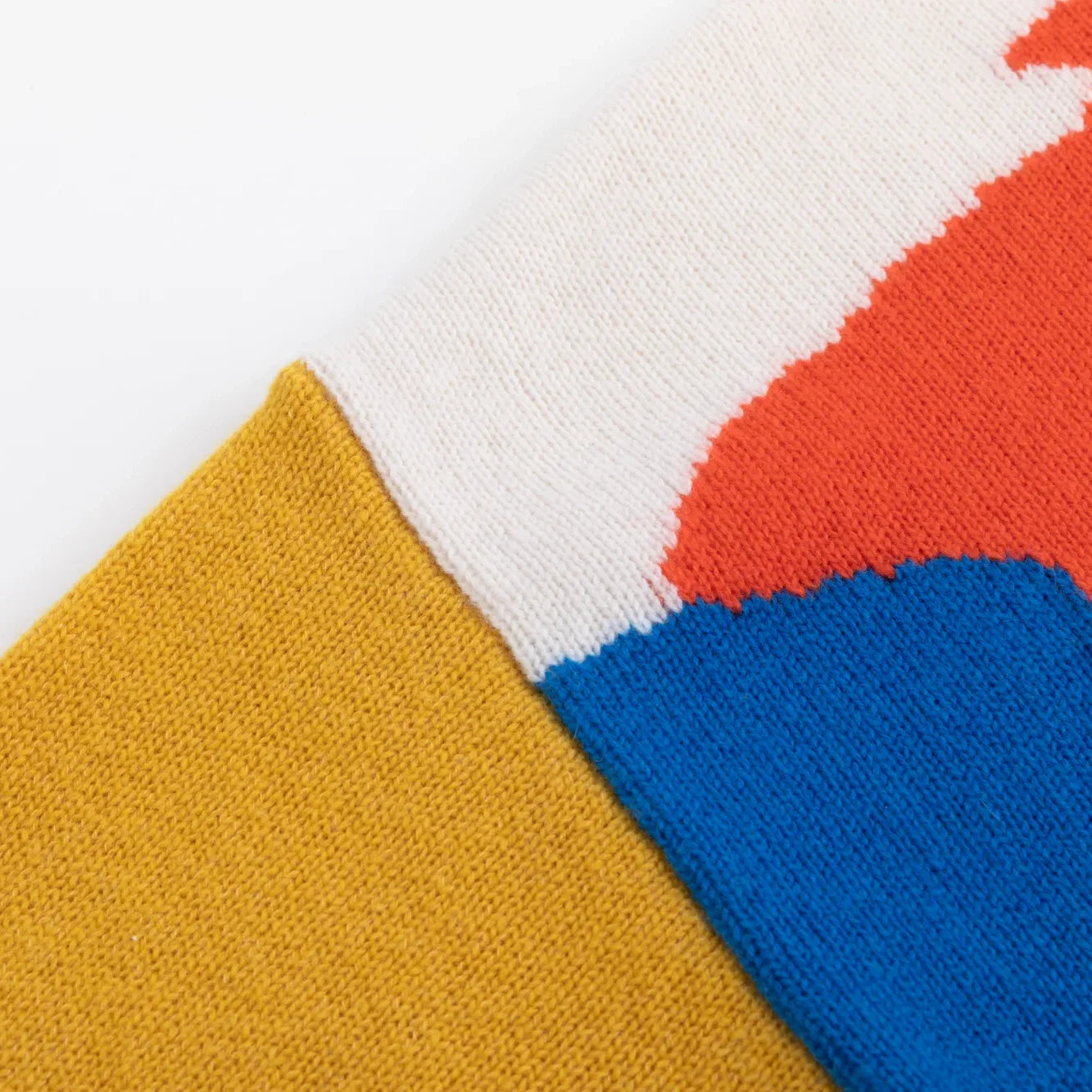 Close-up of mustard, ivory, coral and blue knitted colour blocks