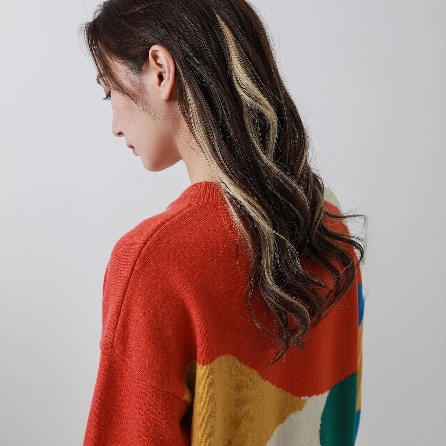 Close-up of the back of a coral multicolour jumper with abstract intarsia shapes.