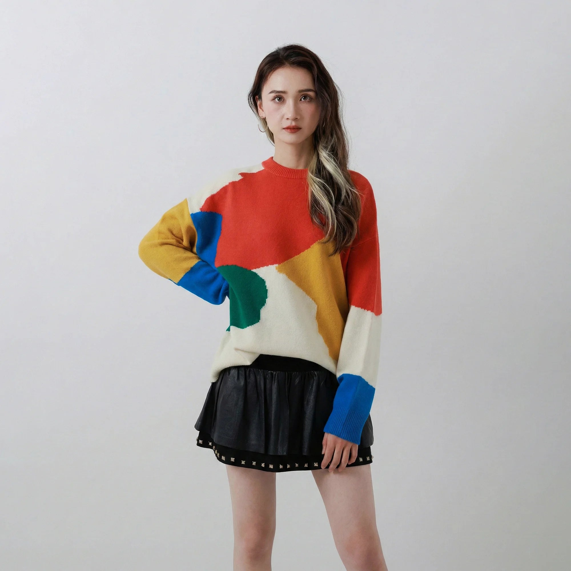 Woman wearing a coral multi merino wool jumper with an abstract colour-block intarsia design and an oversized dropped-shoulder fit.