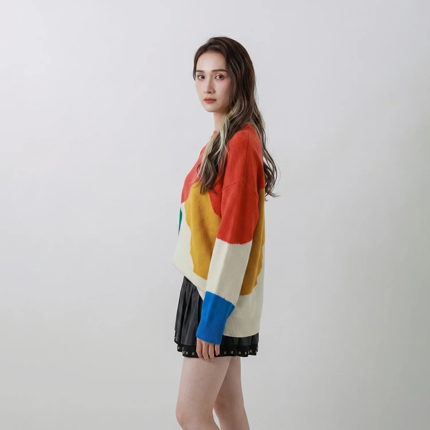 Side view of model wearing a coral multicolour merino wool jumper with an oversized fit.