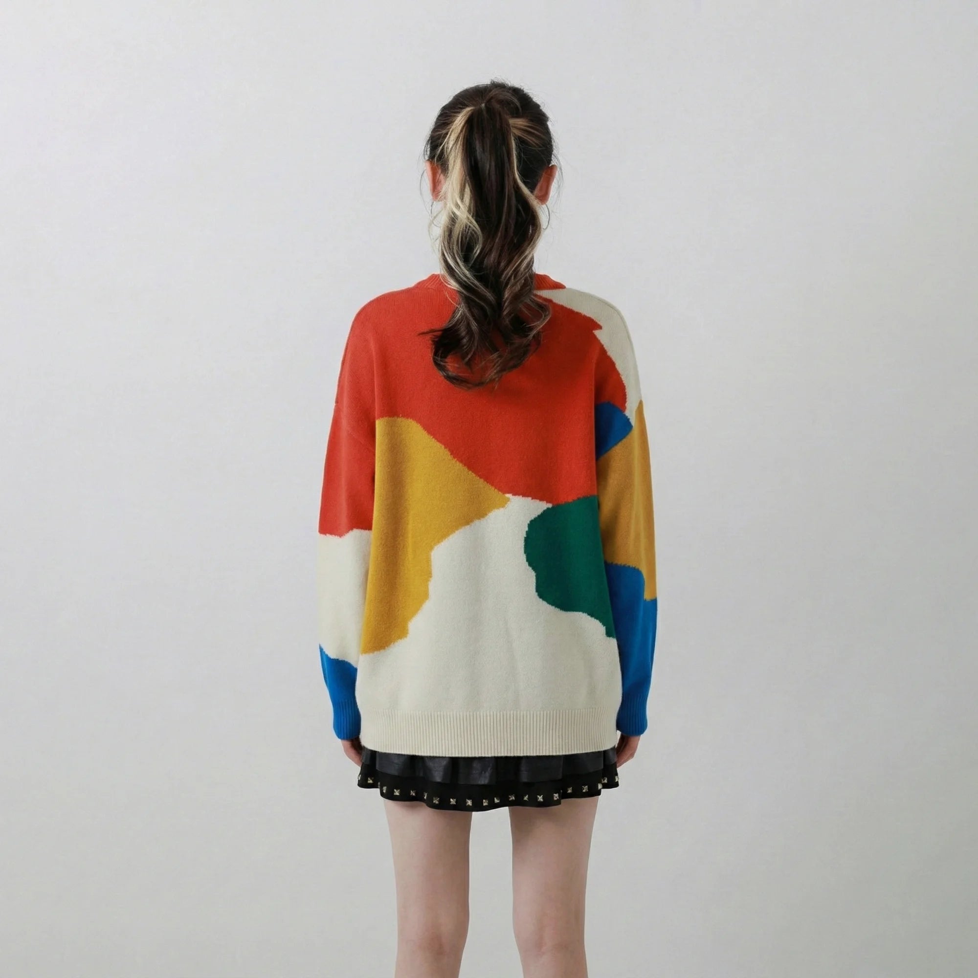 Back view of woman wearing a coral multi merino wool jumper with an oversized dropped-shoulder fit and colour-block sleeves.