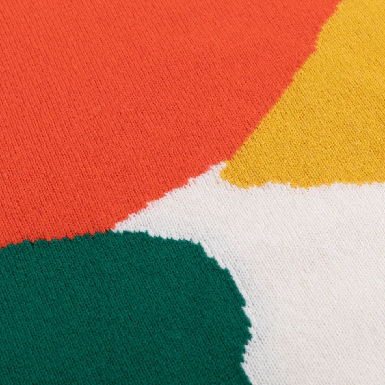 Close-up of coral, mustard, green and ivory knitted colour blocks