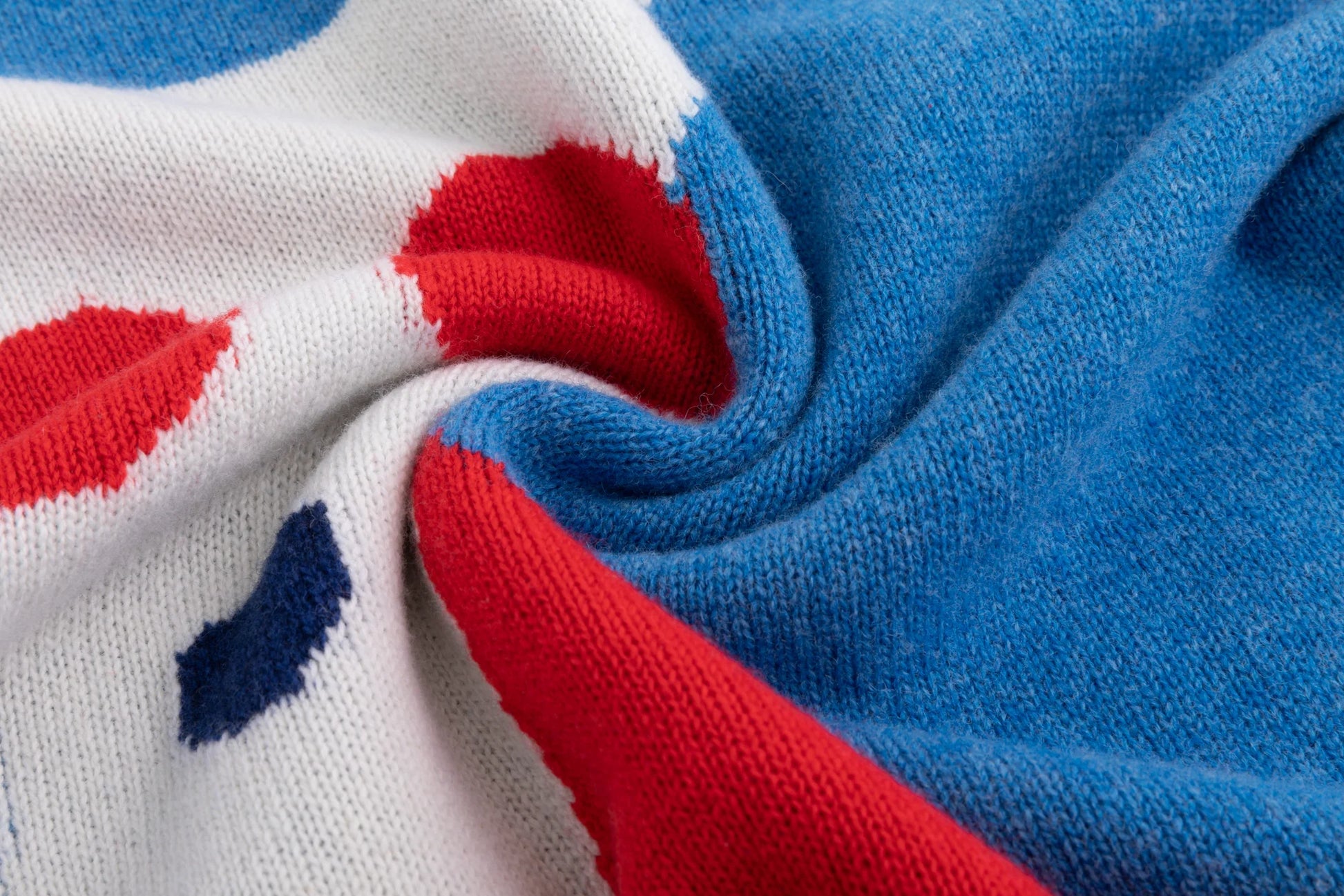 Close-up of the merino wool knit texture and contrasting intarsia colours on the blue jumper.