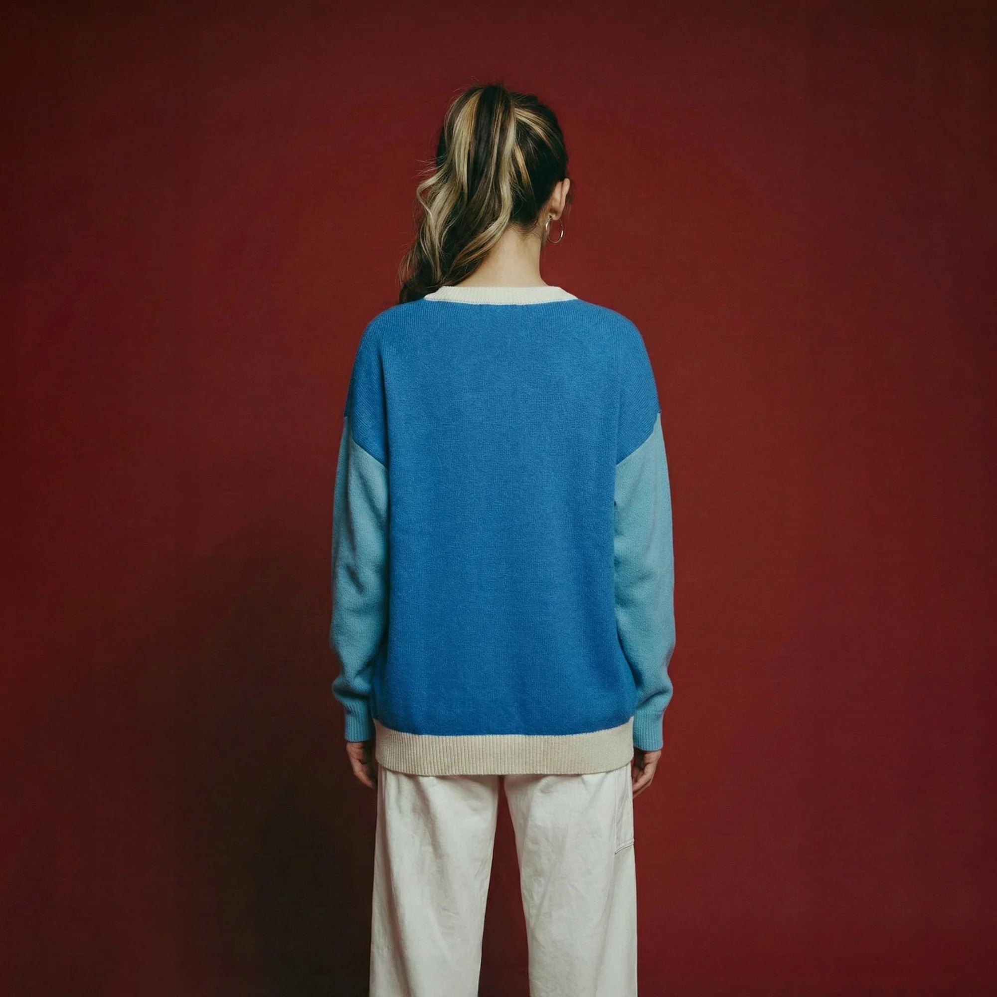 Back view of model wearing a blue merino wool jumper with light blue sleeves and an oversized dropped-shoulder fit.