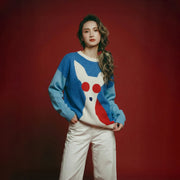 Model wearing a blue merino wool jumper with a contrasting dog intarsia on the front, light blue sleeves and an oversized dropped-shoulder fit.