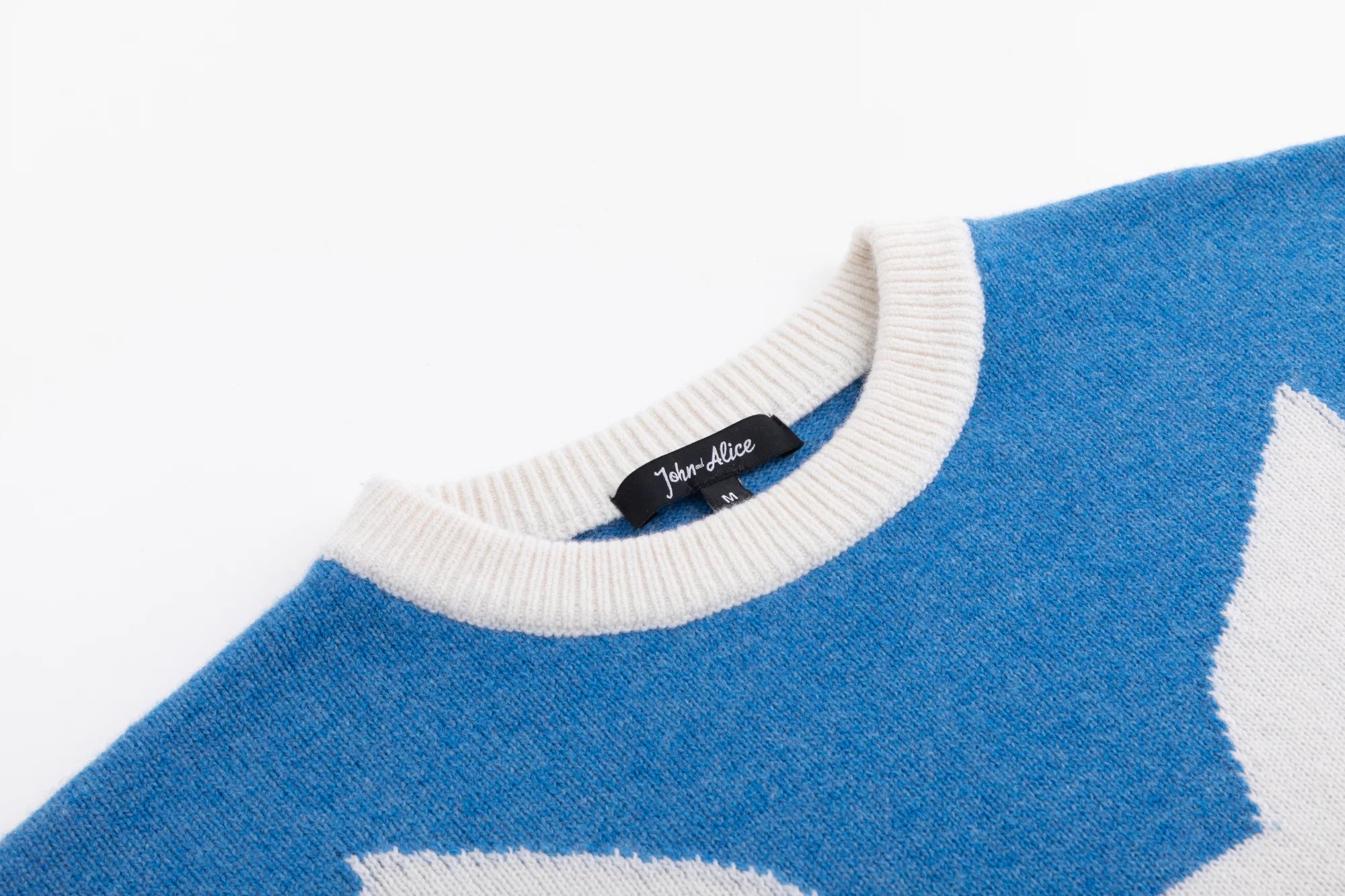 Close-up of the ribbed crew neckline on the blue merino wool jumper.