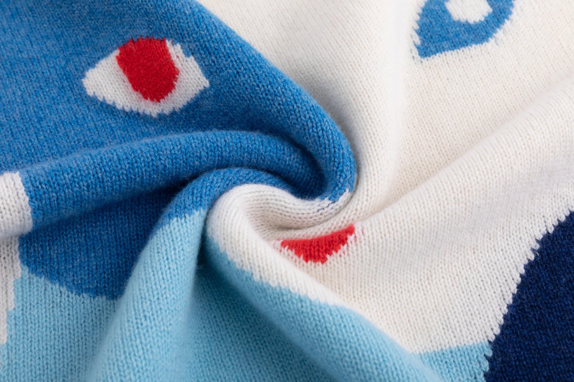 Close-up of the merino wool knit texture and contrasting intarsia colours on the cream jumper.
