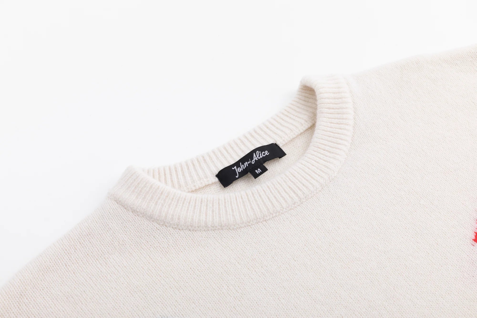 Close-up of the ribbed crew neckline on the cream merino wool jumper.