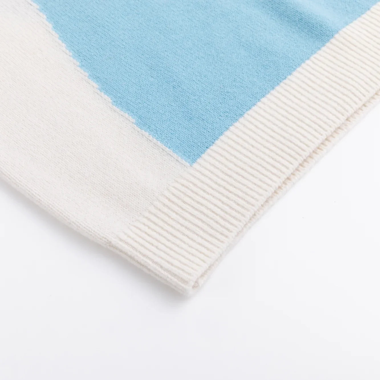 Close-up of the ivory ribbed hem beside the blue intarsia.