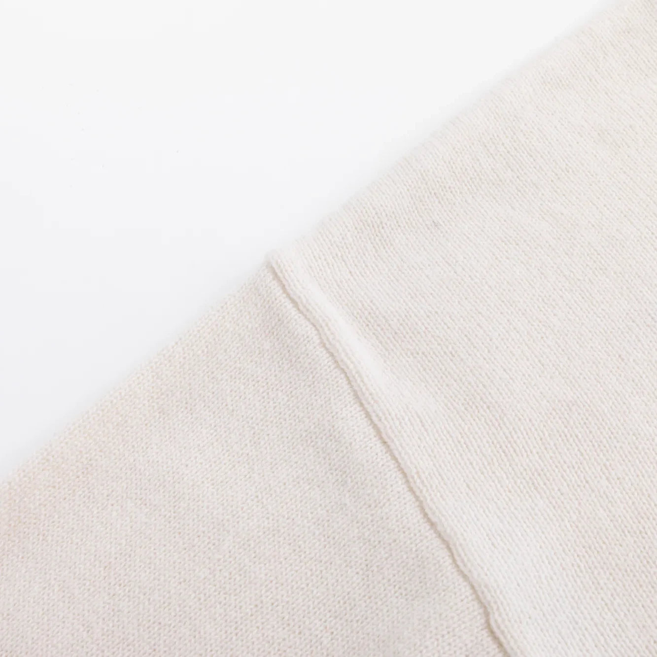 Close-up of the dropped shoulder seam on the ivory knit jumper.