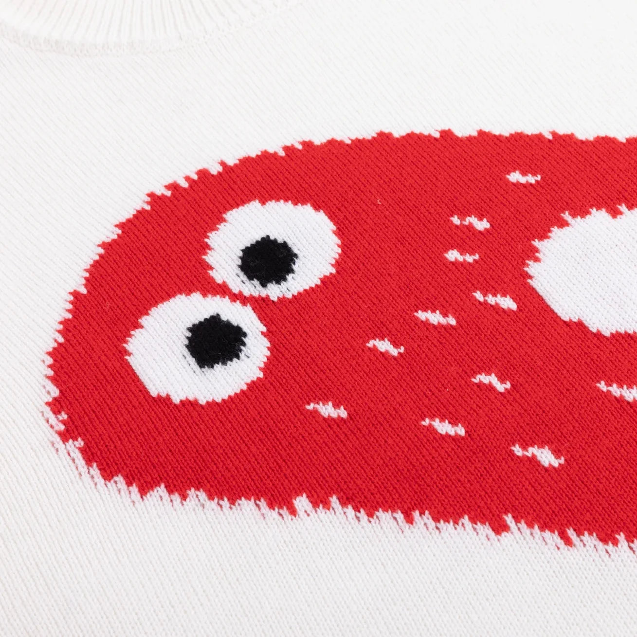Red knitted ghost motif with black and white eyes on an ivory background