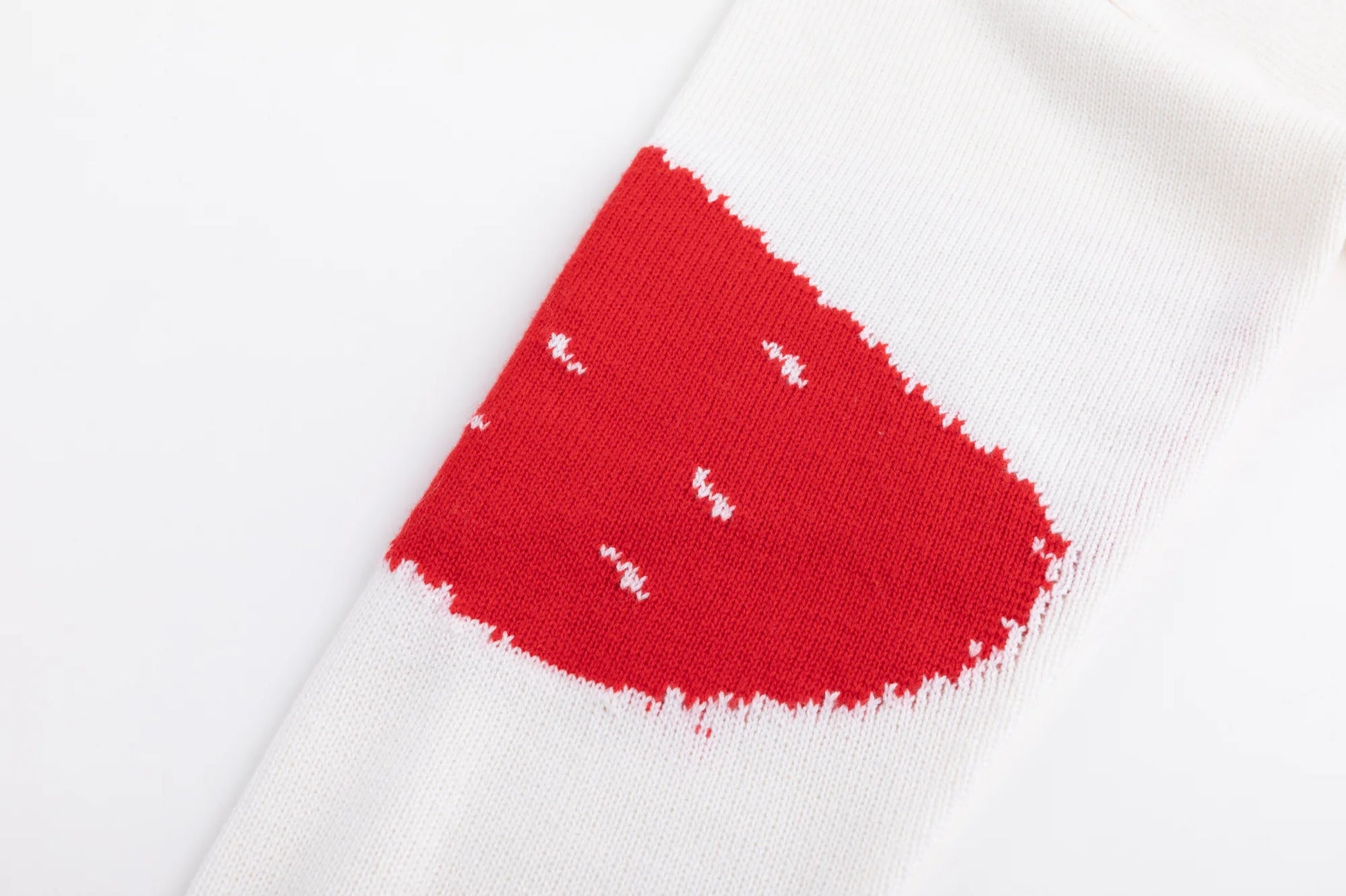 Close-up of the red intarsia panel on the ivory sleeve of the jumper.