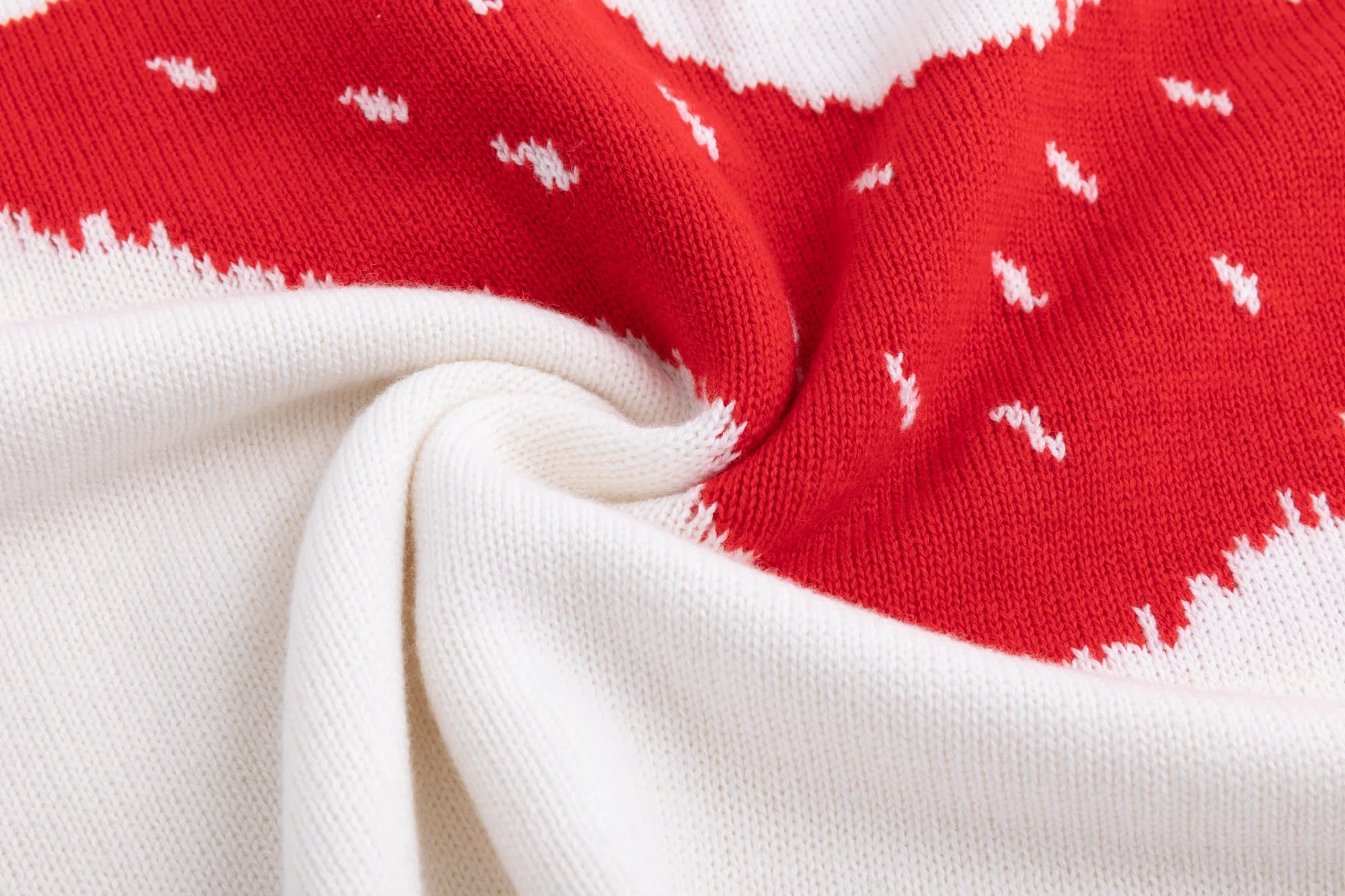 Close-up of the cotton and wool blend knit texture where the red ghost intarsia meets the ivory base.