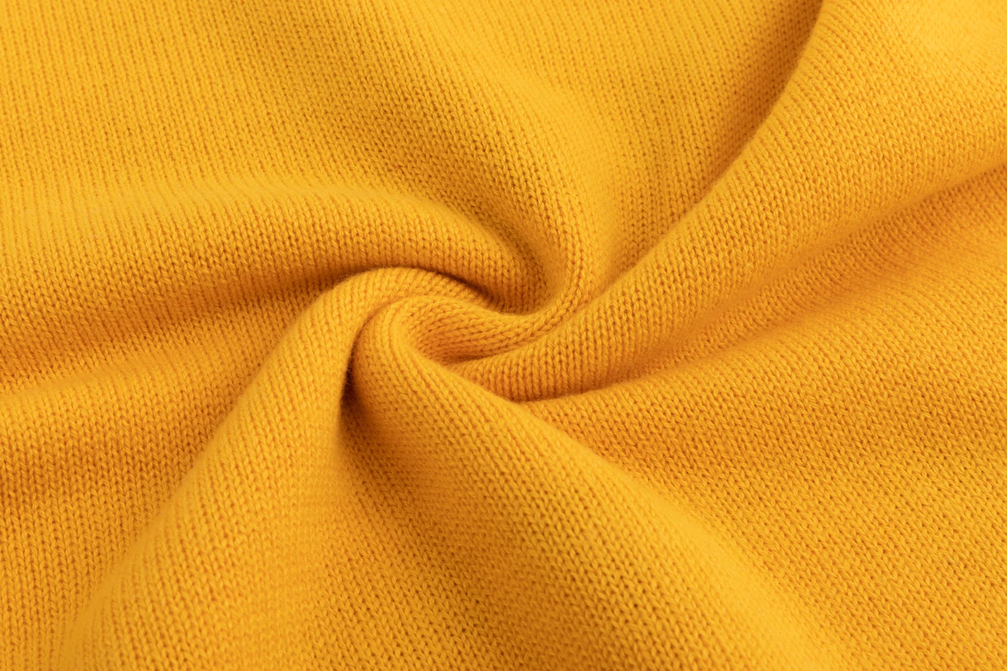 Close-up of the cotton and wool blend knit texture on the mustard yellow jumper.