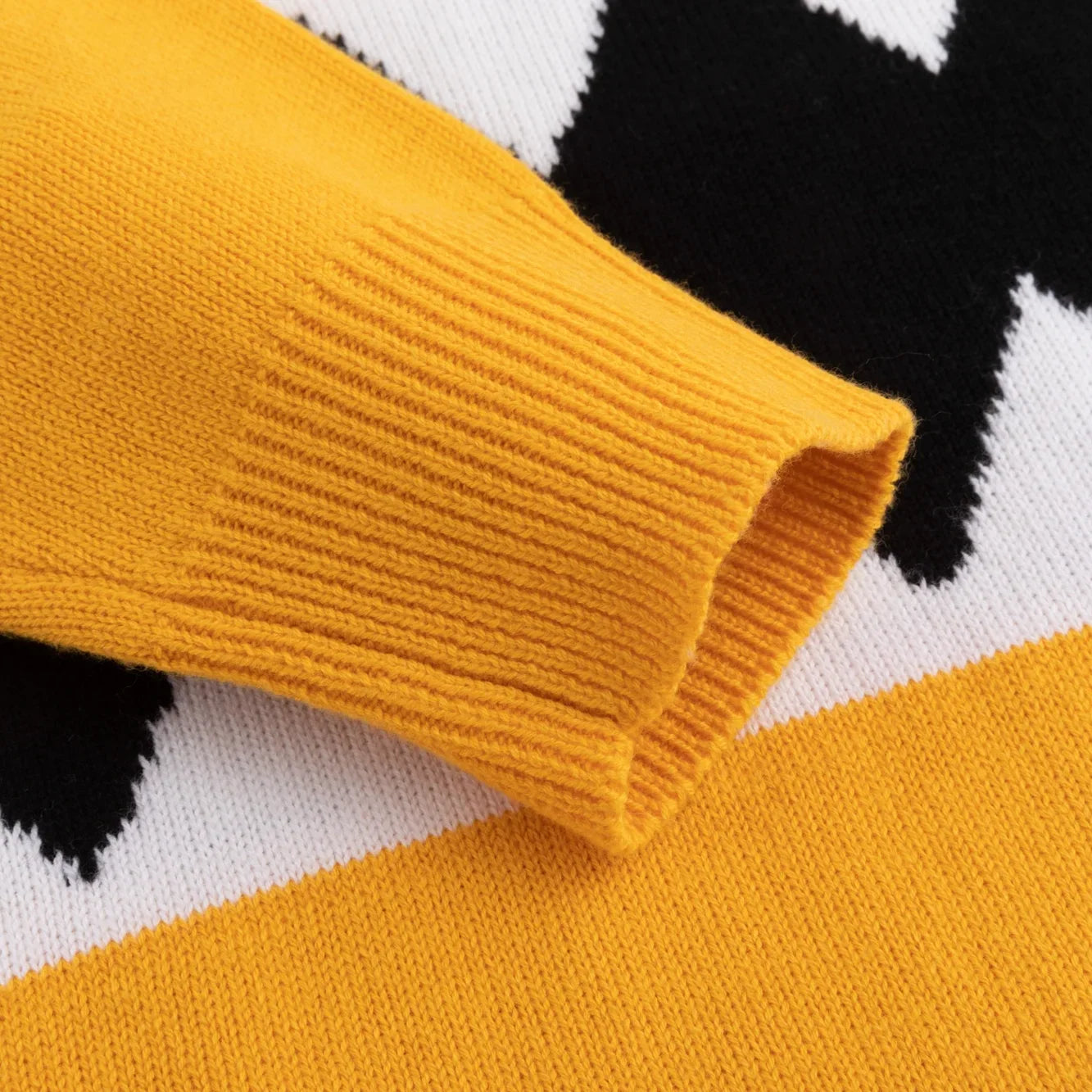 Mustard yellow ribbed cuff over a black and white knitted pattern