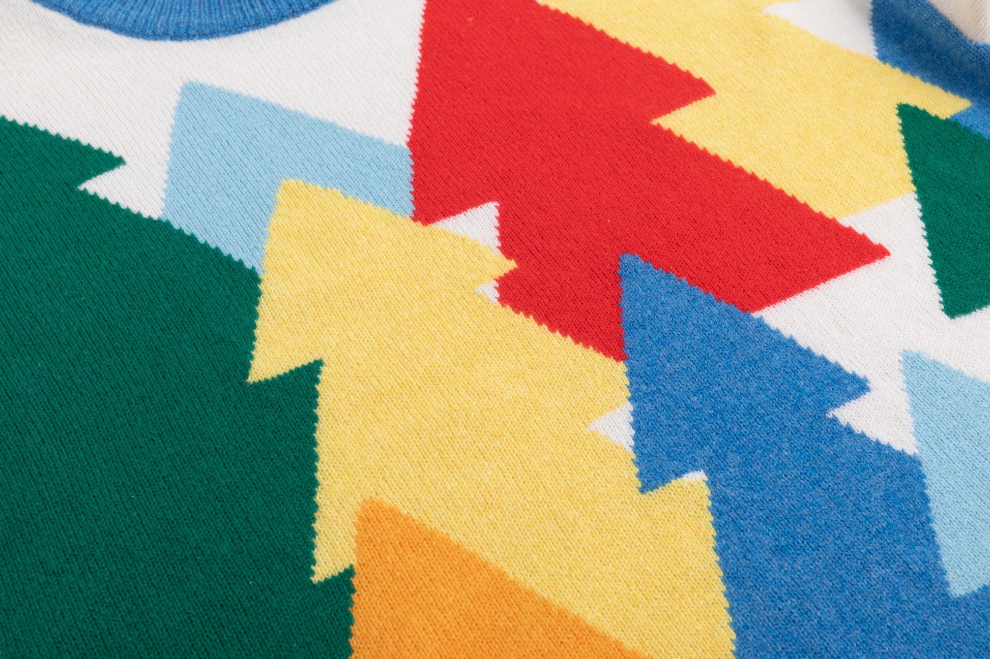 Close-up of the multicolour forest intarsia with layered tree motifs on the ivory jumper.