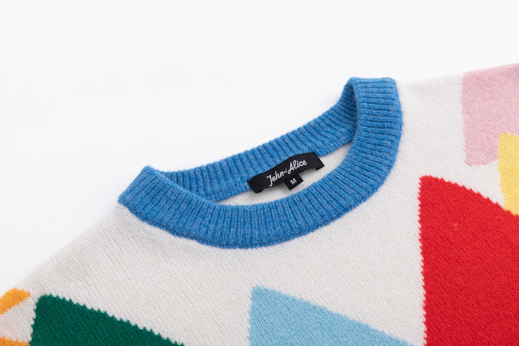 Close-up of the ribbed crew neckline on the ivory jumper with part of the forest intarsia visible.