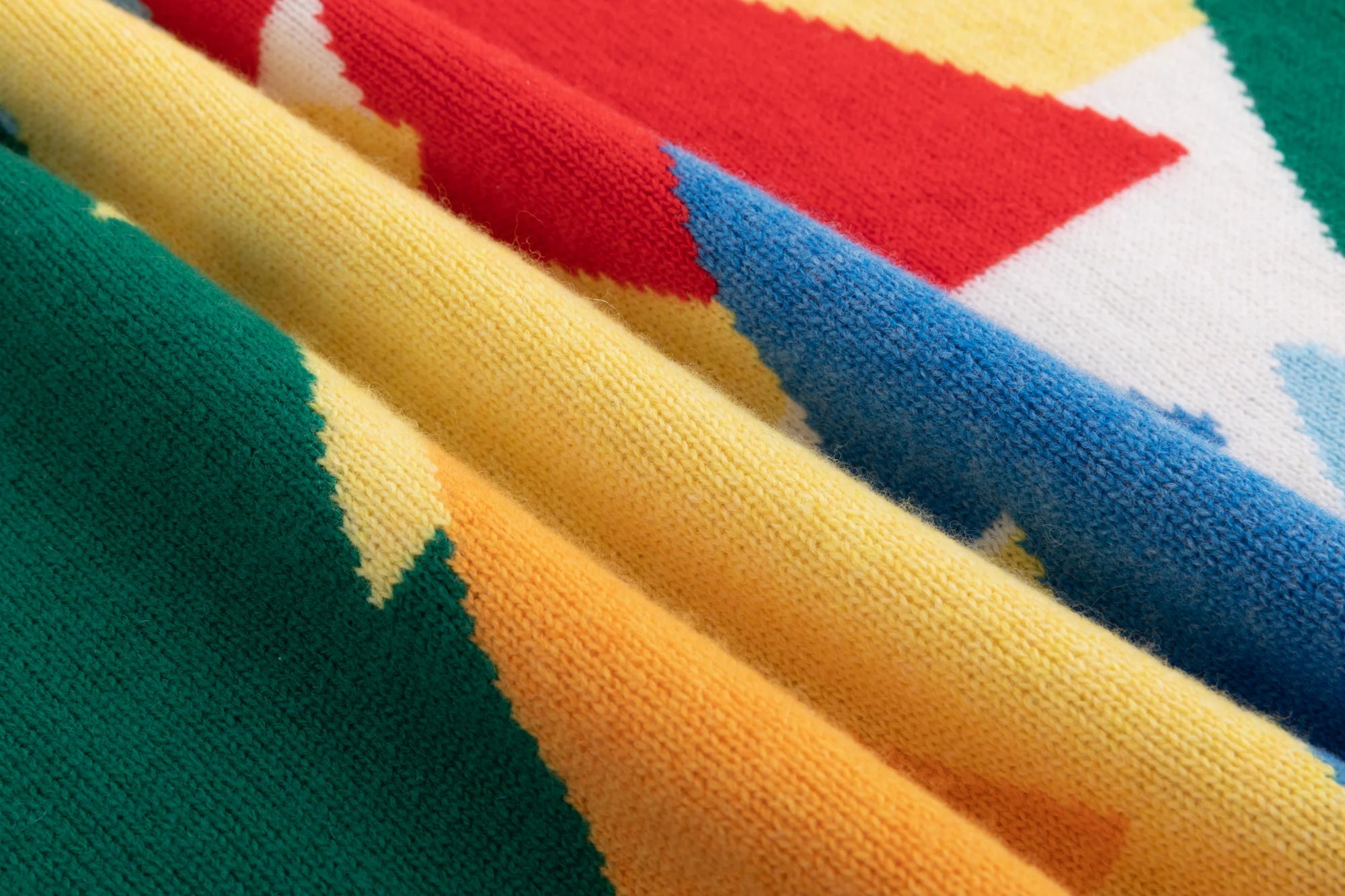 Close-up of the merino wool knit texture and multicolour intarsia on the ivory jumper.