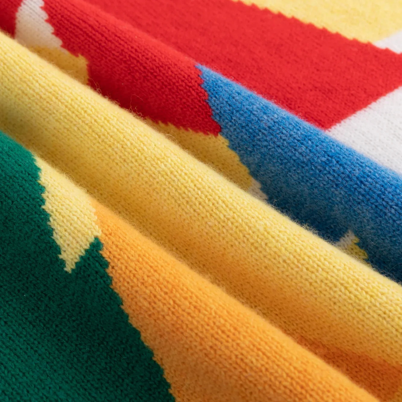 Folded knit fabric with green, yellow, red and blue tree motifs
