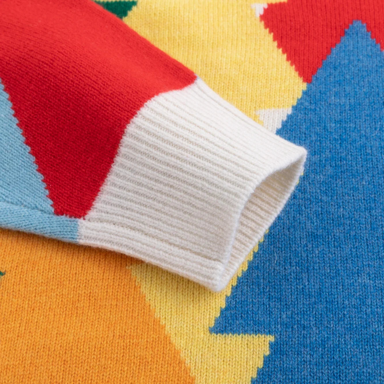 Ivory ribbed cuff beside colourful knitted tree motifs