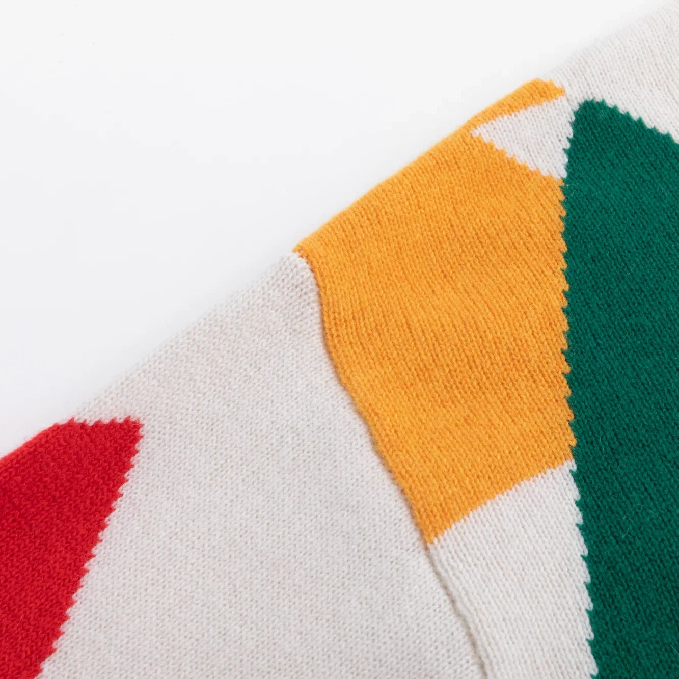 Shoulder seam with orange, green and red knitted tree motifs