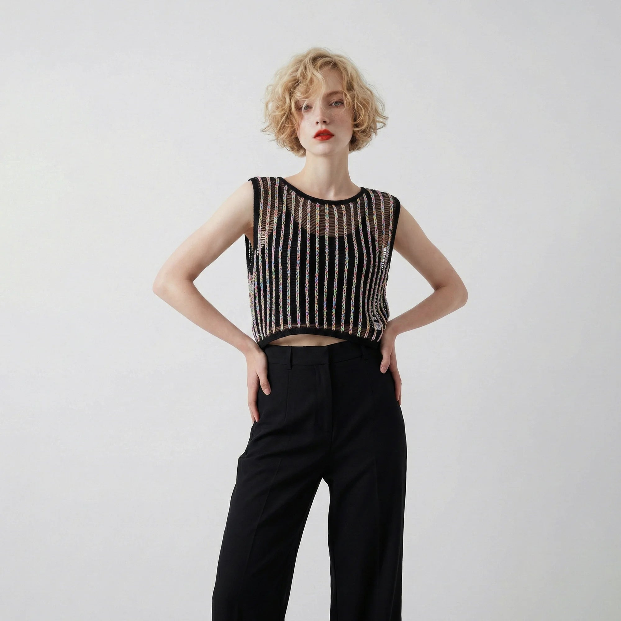 Model wearing a black crochet top with multicolour vertical stripes and a sleeveless cropped silhouette.