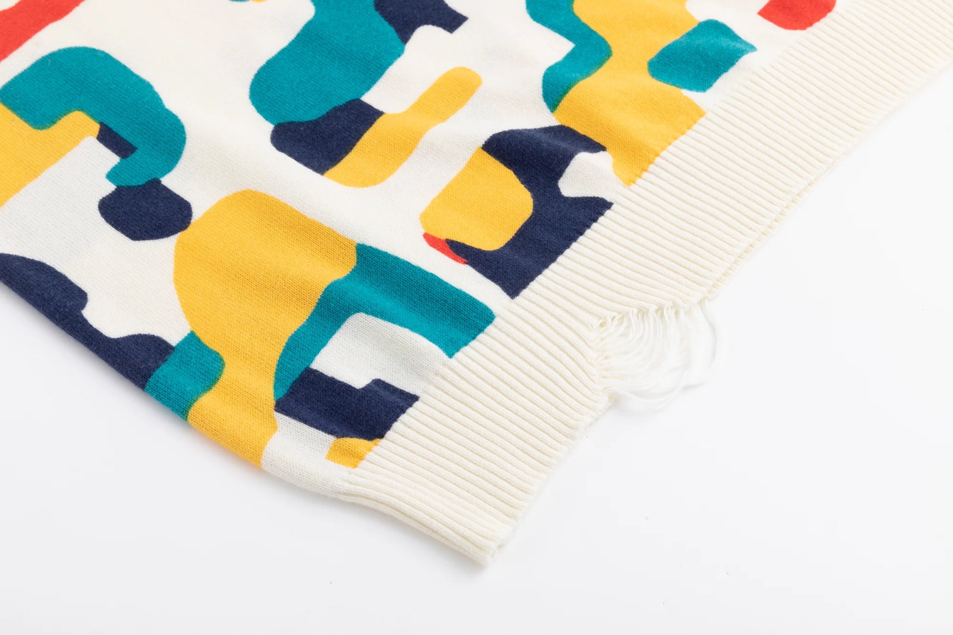 Close-up of the distressed ribbed hem on the ivory jumper with the abstract horse print beside it.