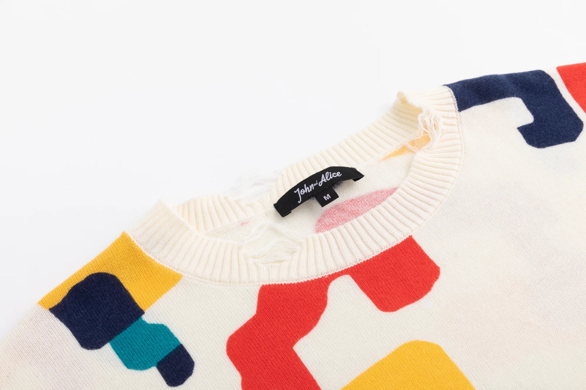 Close-up of the ribbed crew neckline on the ivory jumper with part of the abstract horse print visible.