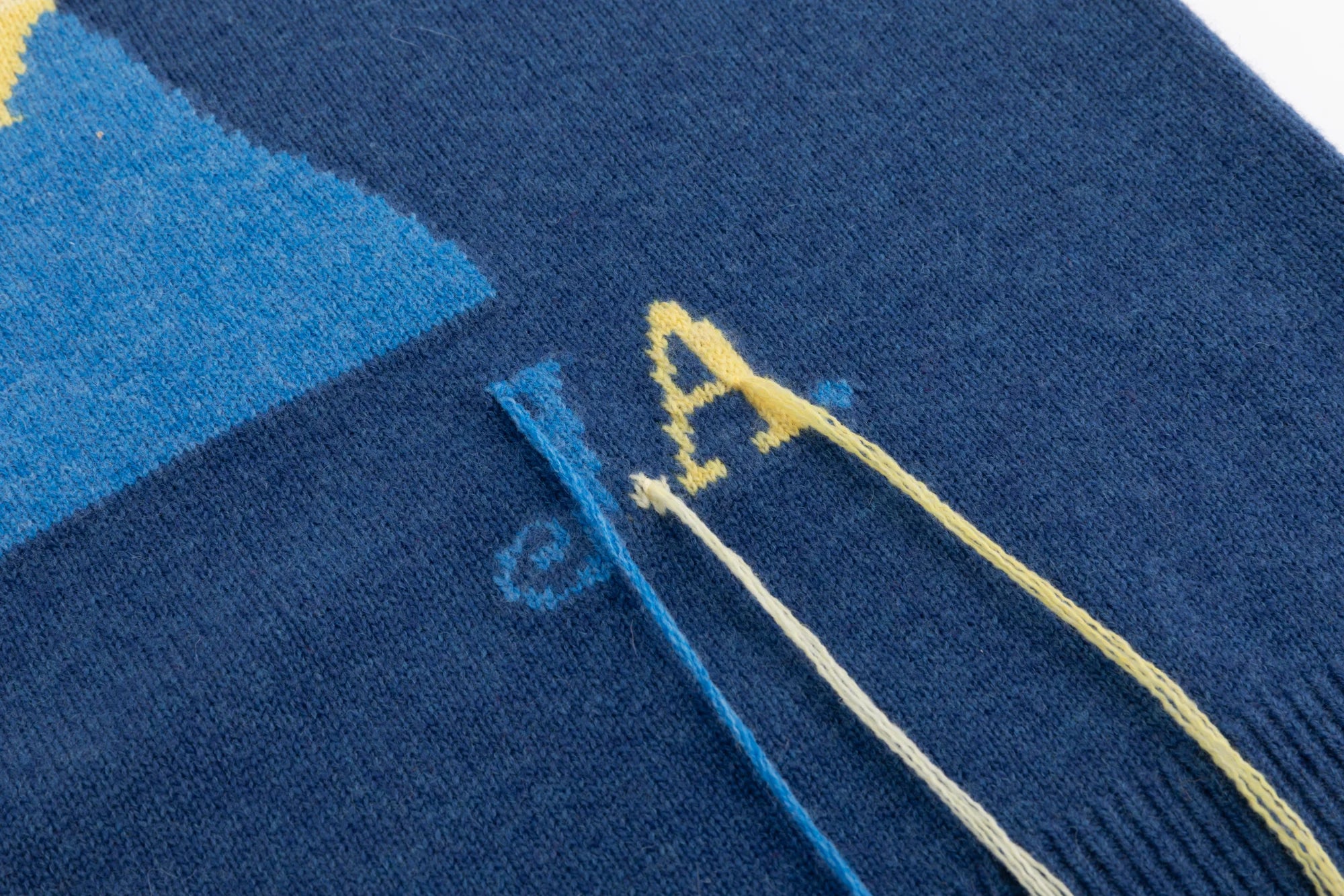 Close-up of the JA lettering and tassel detail on the blue jumper.