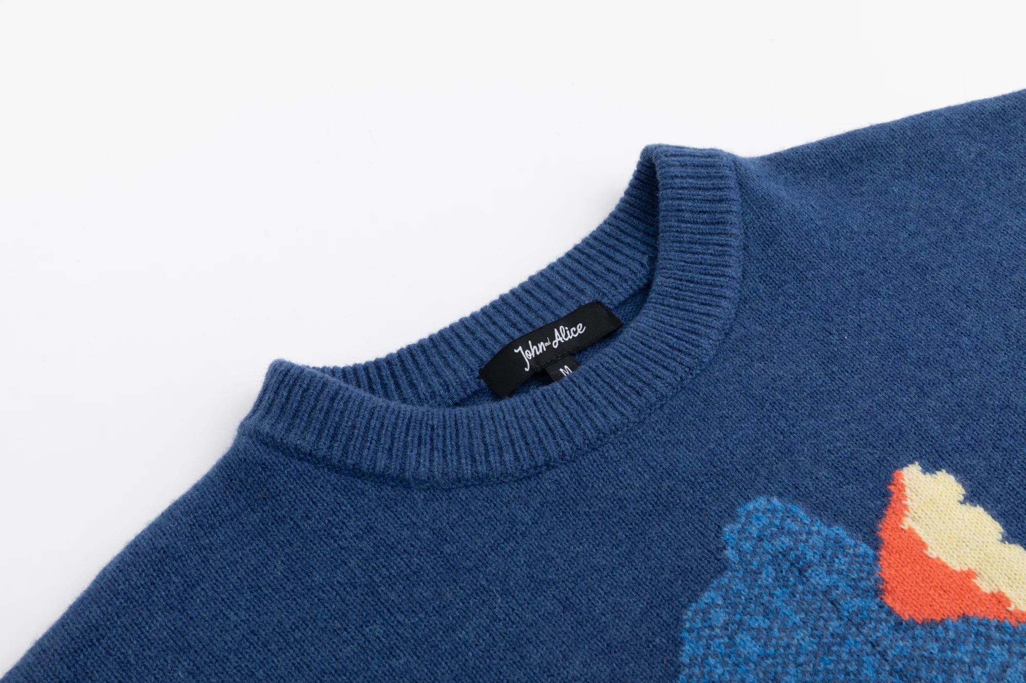 Close-up of the ribbed crew neckline on the blue jumper with part of the front intarsia visible.