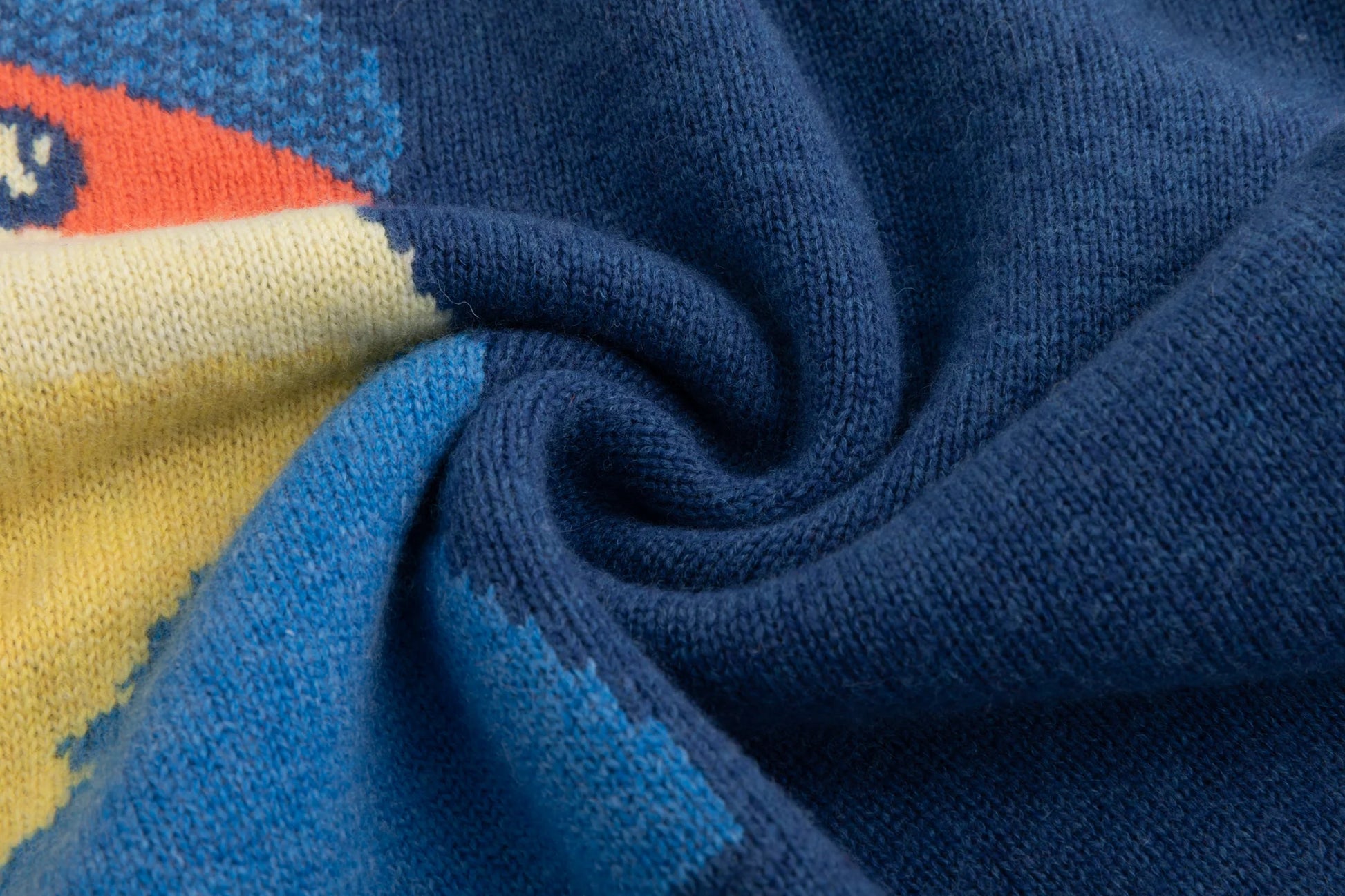 Close-up of the merino wool knit texture beside the cat intarsia on the blue jumper.
