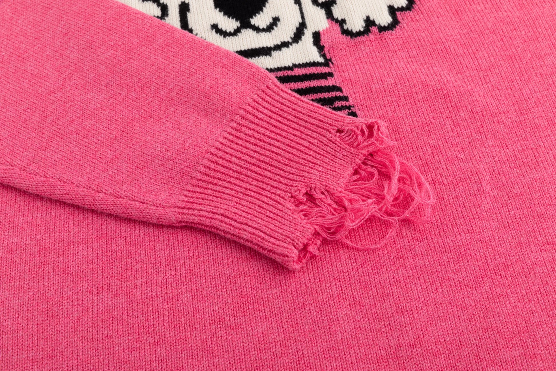 Close-up of the distressed ribbed cuff on the pink jumper with part of the front jacquard visible.