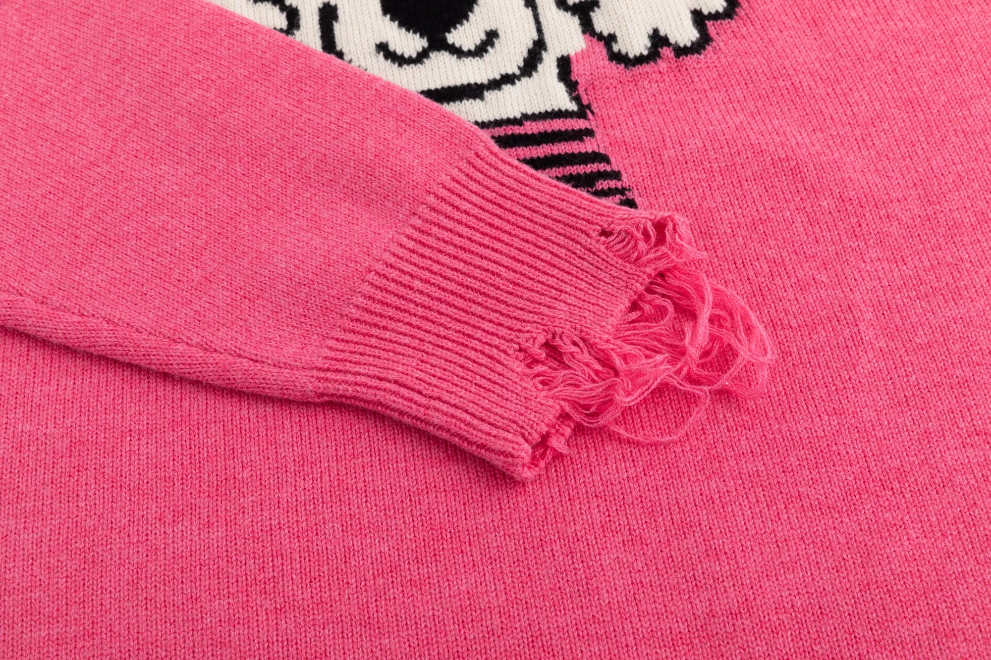 Close-up of the distressed ribbed cuff on the pink jumper with part of the front jacquard visible.
