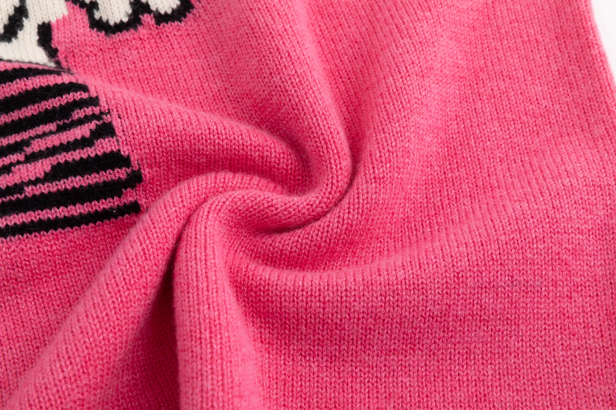 Close-up of the merino wool knit texture on the pink jumper beside the teddy dog jacquard.