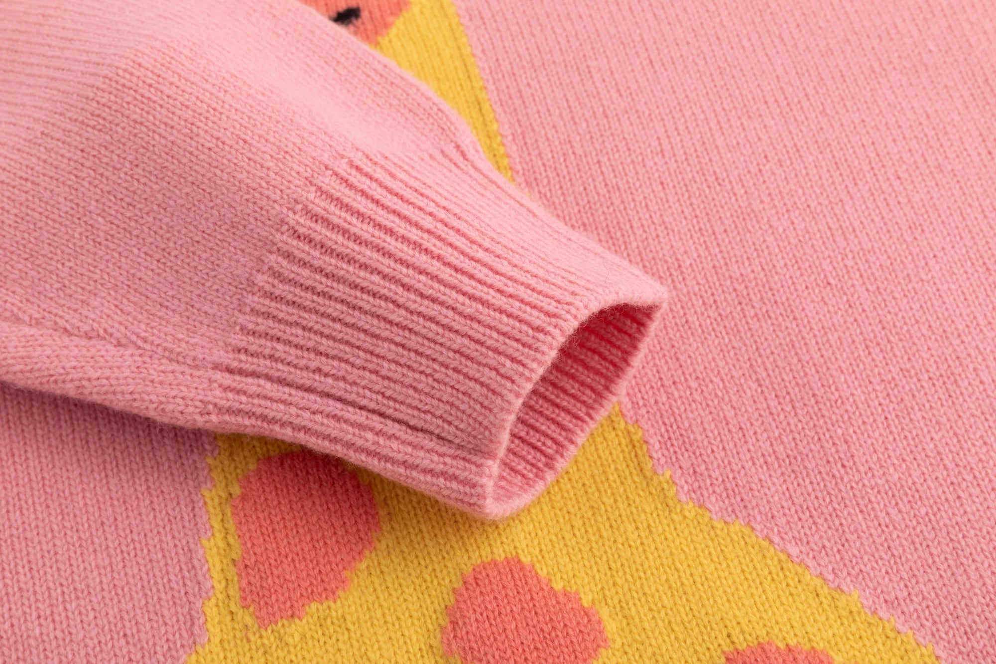 Close-up of the ribbed cuff on the pink jumper with part of the giraffe intarsia visible.