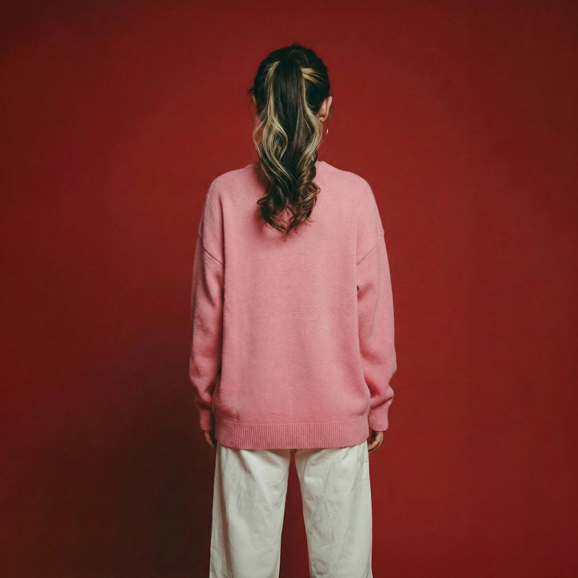 Back view of model wearing a pink merino wool jumper with an oversized dropped-shoulder fit.