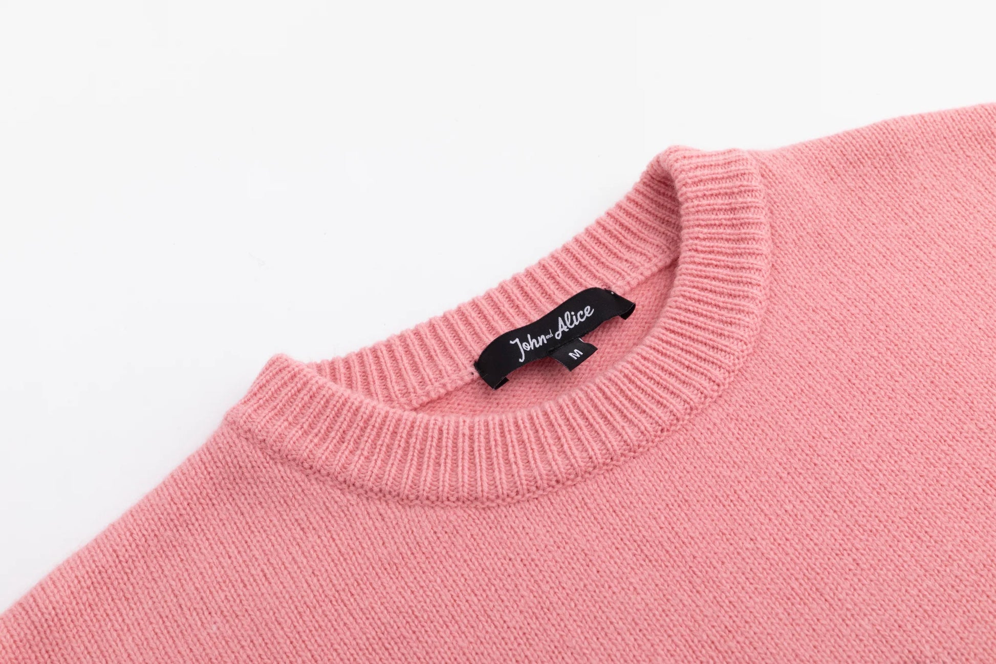 Close-up of the ribbed crew neckline on the pink jumper.