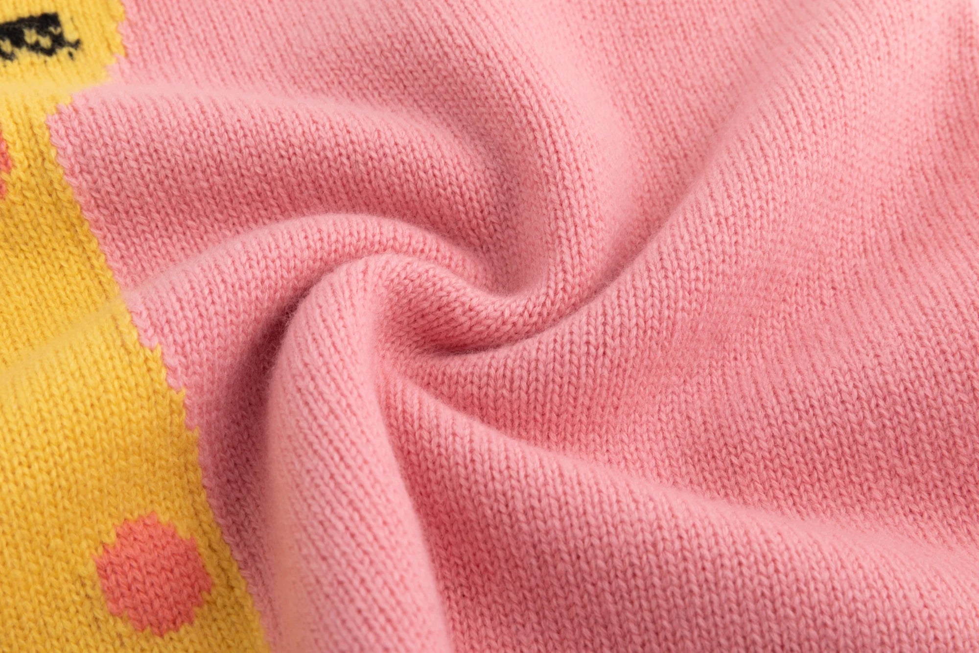 Close-up of the merino wool knit texture on the pink jumper beside the giraffe intarsia.