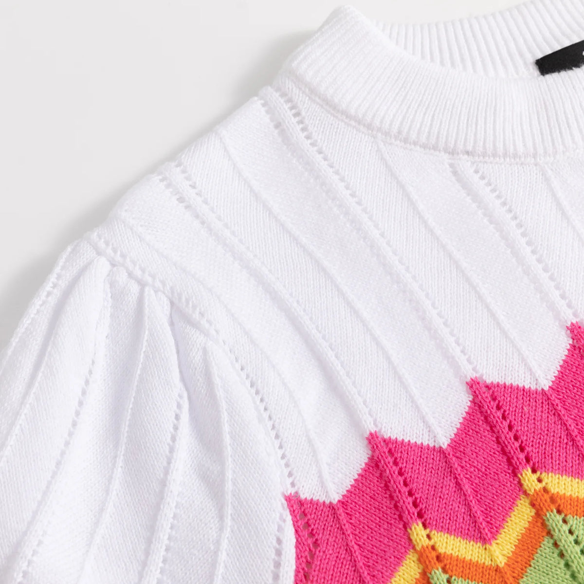 White pointelle knit detail transitioning into pink and orange zigzag colourwork.